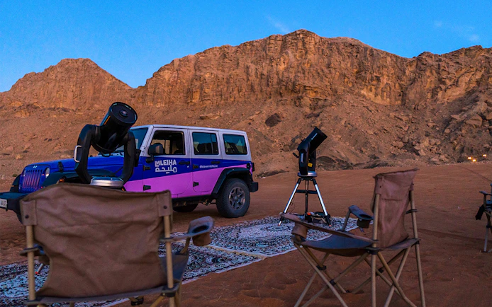 Stargazing setup with telescopes and chairs in Mleiha desert.