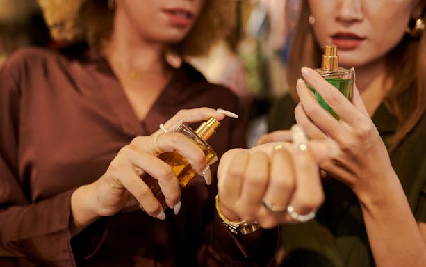 Women testing perfumes on wrists in a store setting.