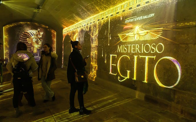 Visitors exploring Mysterious Egypt exhibit with illuminated hieroglyphs and pharaoh imagery.