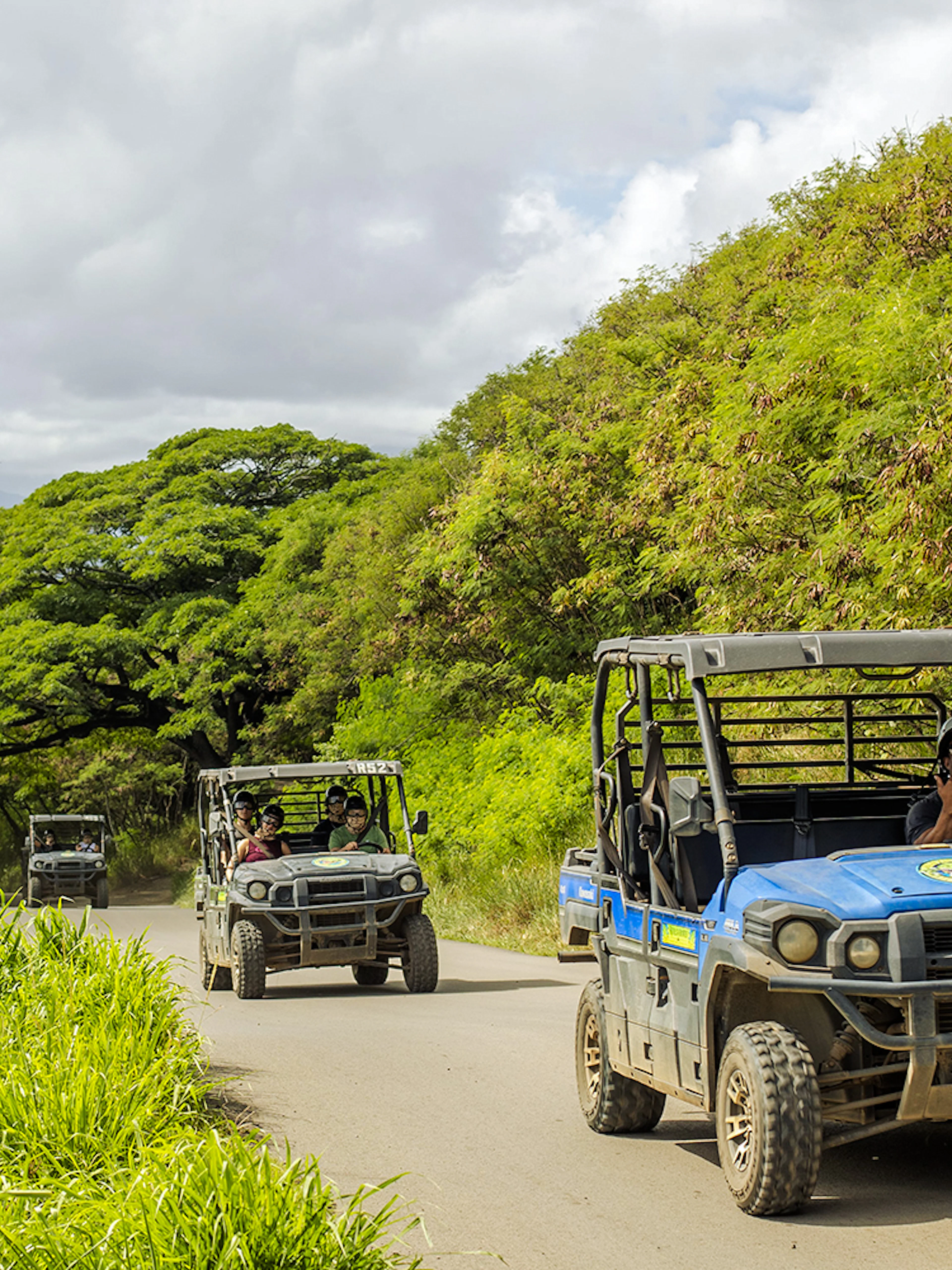 UTV Raptor vehicles on a scenic trail at Kualoa Ranch, Hawaii, with lush greenery and ocean view.
