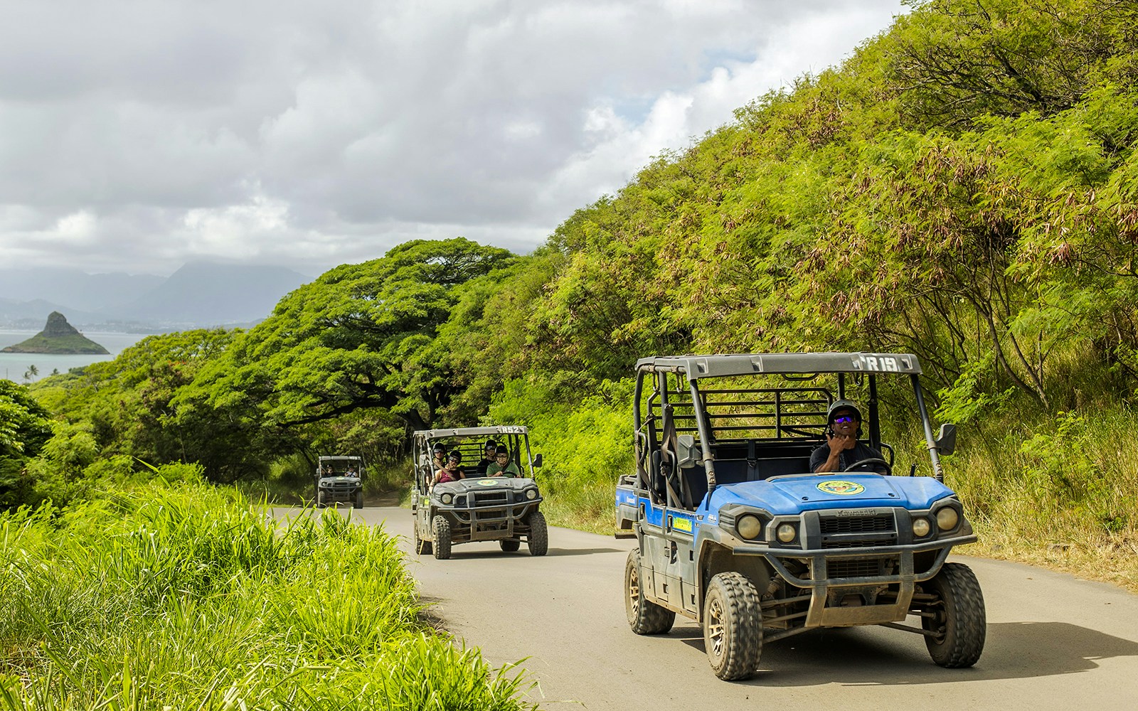 UTV Raptor vehicles on a scenic trail at Kualoa Ranch, Hawaii, with lush greenery and ocean view.