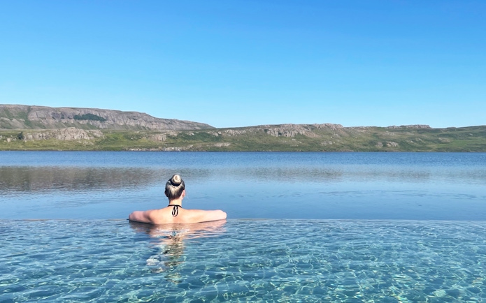 Person relaxing in Vök Baths infinity pool overlooking Lake Urriðavatn, Egilsstaðir.