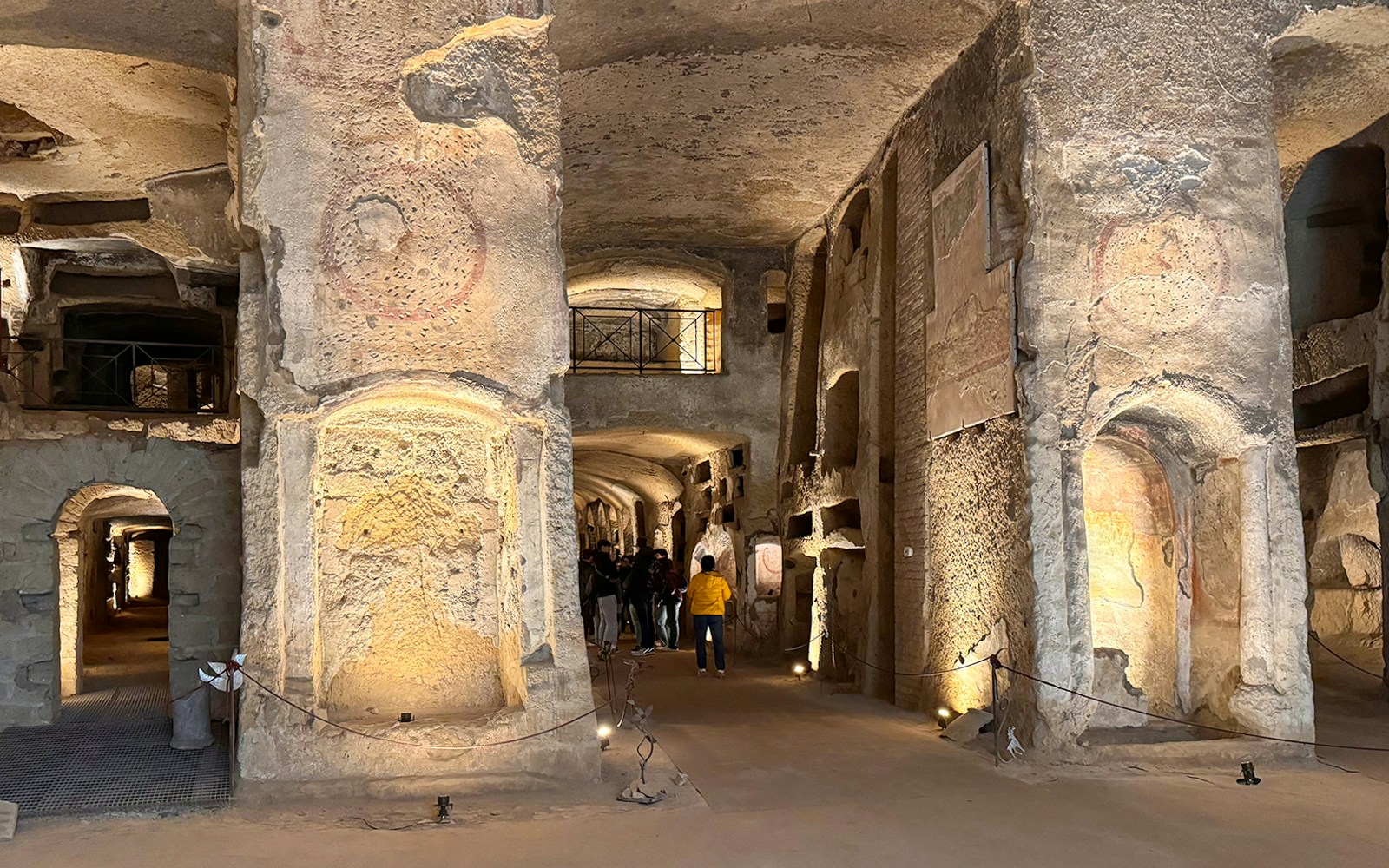 Visitors exploring ancient tunnels at Catacombs of San Gennaro, Naples.