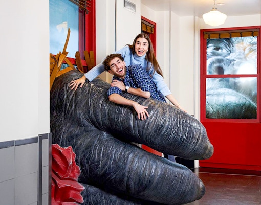 People posing on King Kong's hand inside the Empire State Building, NYC.