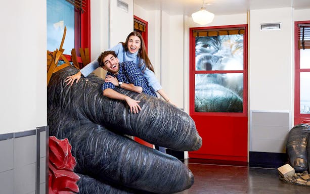 People posing on King Kong's hand inside the Empire State Building, NYC.