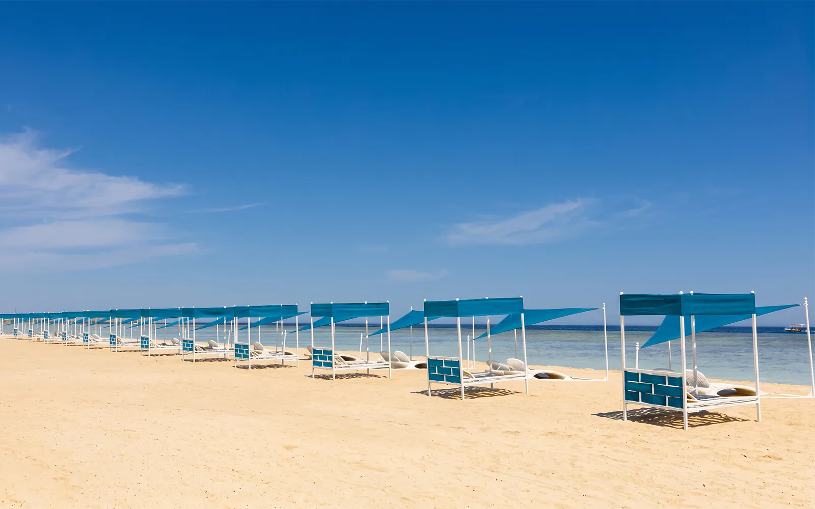 Sun loungers under blue canopies on Bianca Island beach, Hurghada.