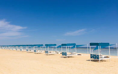Sun loungers under blue canopies on Bianca Island beach, Hurghada.