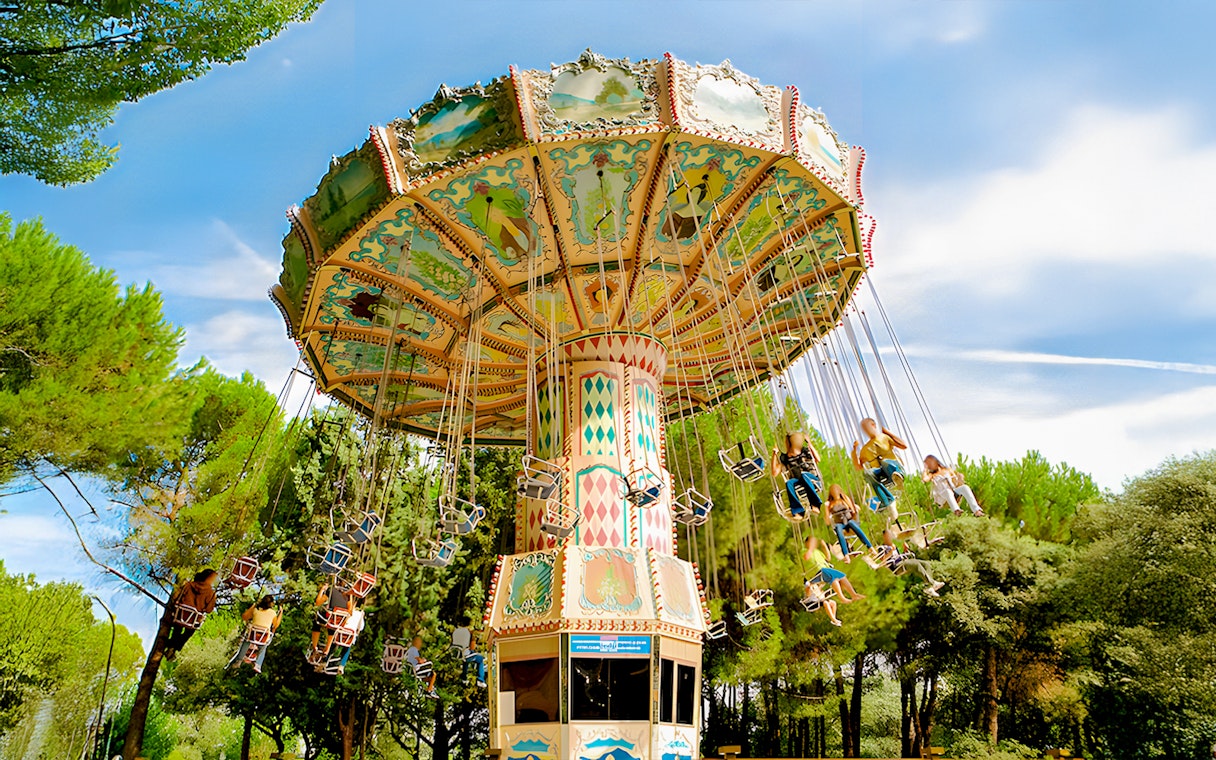 Flying chairs ride at Parque de Atracciones de Madrid with people enjoying the swing.