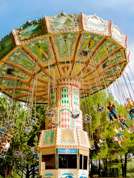 Flying chairs ride at Parque de Atracciones de Madrid with people enjoying the swing.