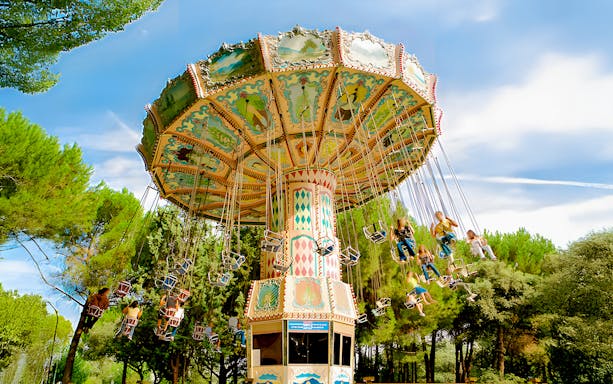 Flying chairs ride at Parque de Atracciones de Madrid with people enjoying the swing.