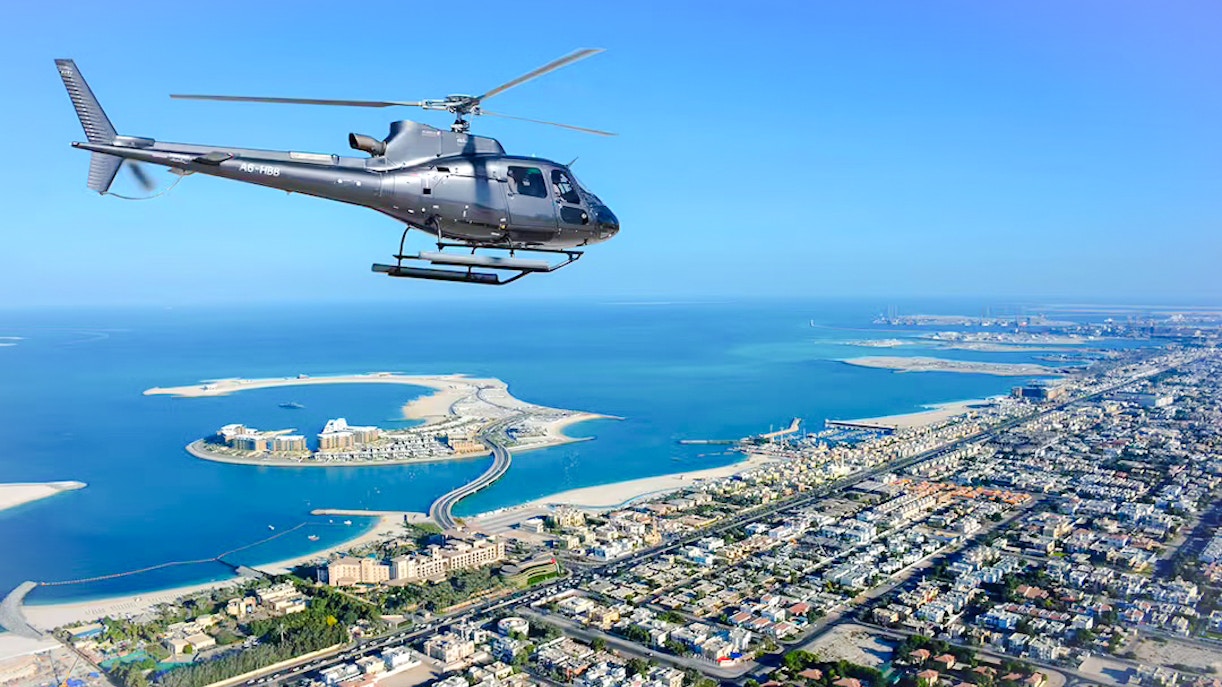 Helicopter flying over Dubai coastline with Palm Jumeirah in view.