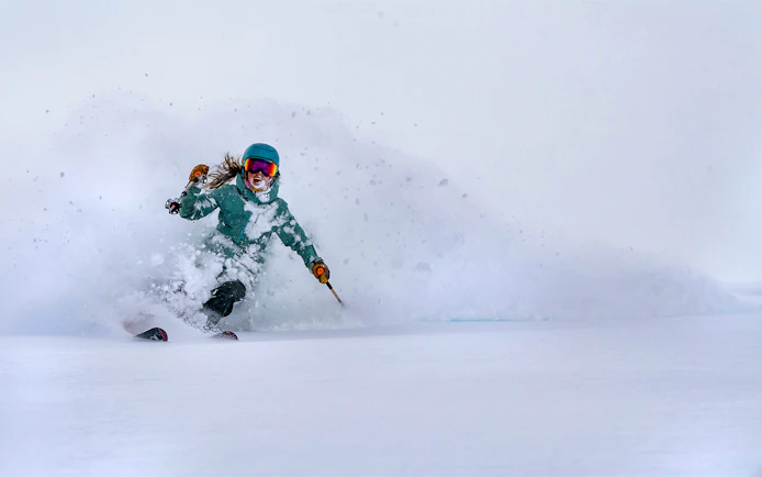 Skier navigating fresh powder snow, showcasing Ikon Pass experience.