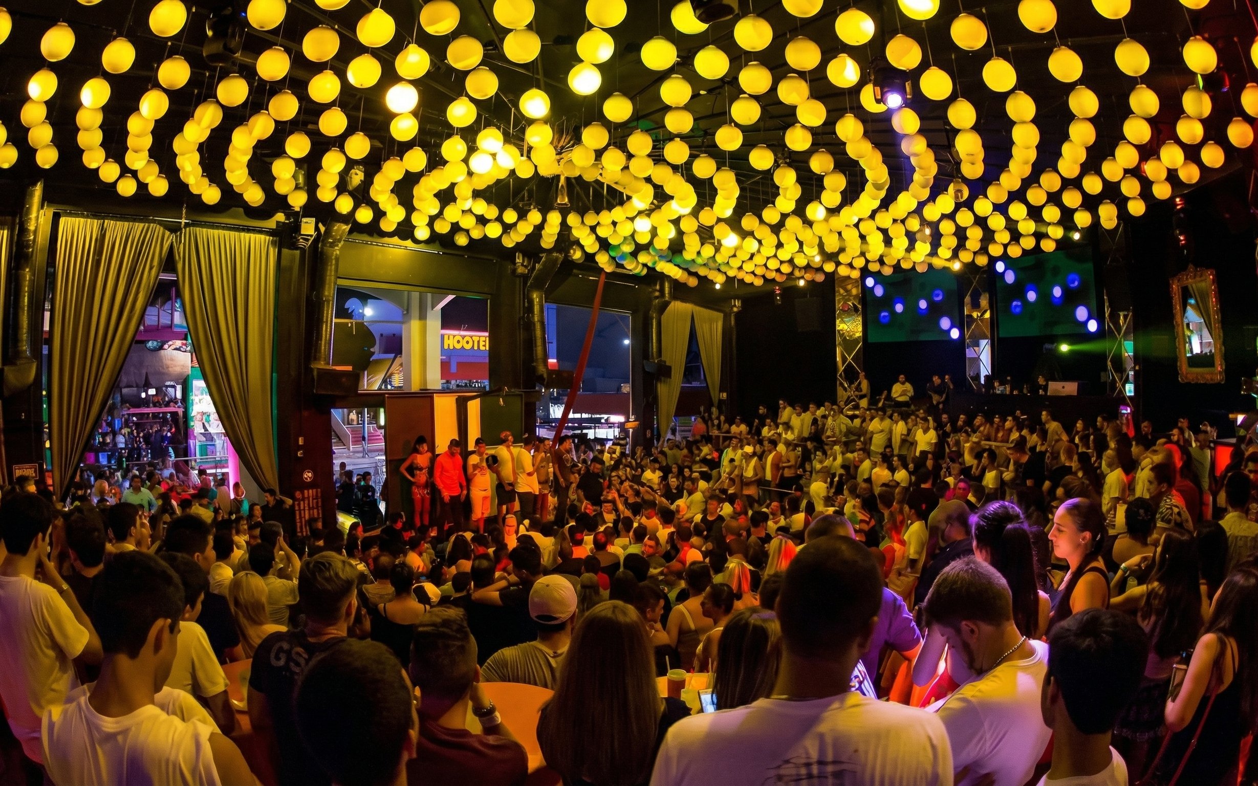 Crowded dance floor at Mandala Nightclub Cancun with vibrant yellow lights overhead.