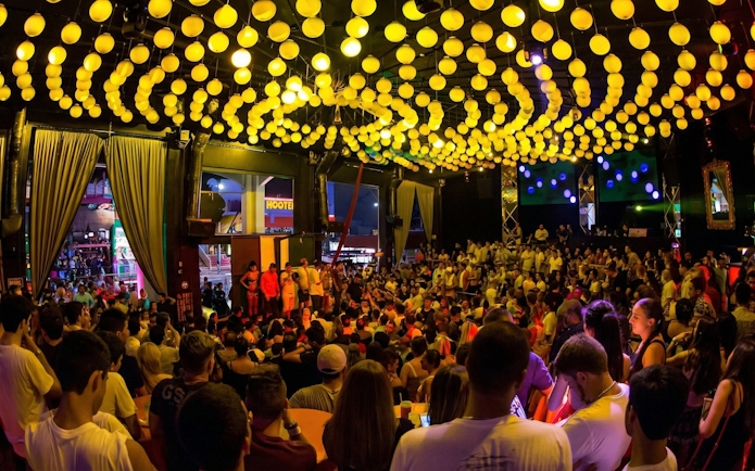 Crowded dance floor at Mandala Nightclub Cancun with vibrant yellow lights overhead.