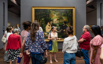 Group tour at Musée d’Orsay viewing Impressionist painting with guide.