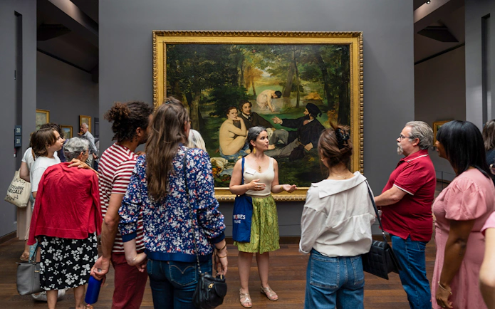Group tour at Musée d’Orsay viewing Impressionist painting with guide.