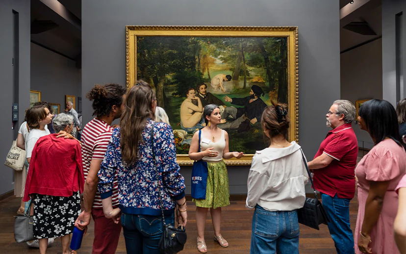 Group tour at Musée d’Orsay viewing Impressionist painting with guide.