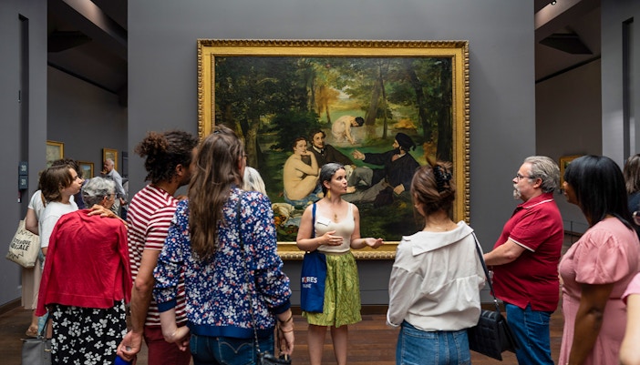 Group tour at Musée d’Orsay viewing Impressionist painting with guide.