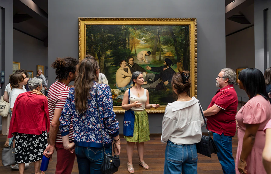 Group tour at Musée d’Orsay viewing Impressionist painting with guide.