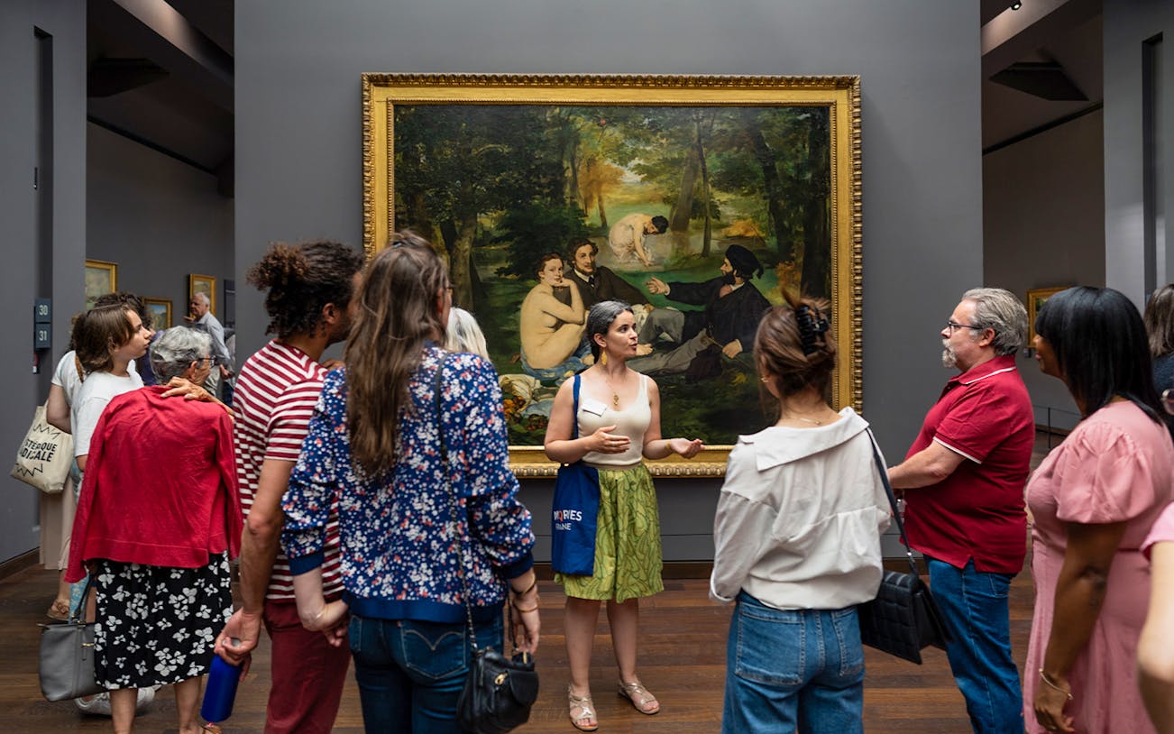 Group tour at Musée d’Orsay viewing Impressionist painting with guide.