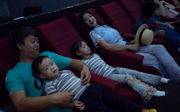 Family seated in planetarium chairs, children observing the dome.