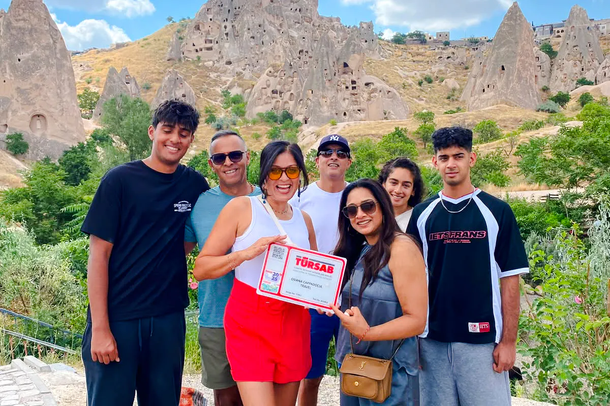 Group of tourists at Zelve Open Air Museum, Cappadocia, with rock formations in the background.