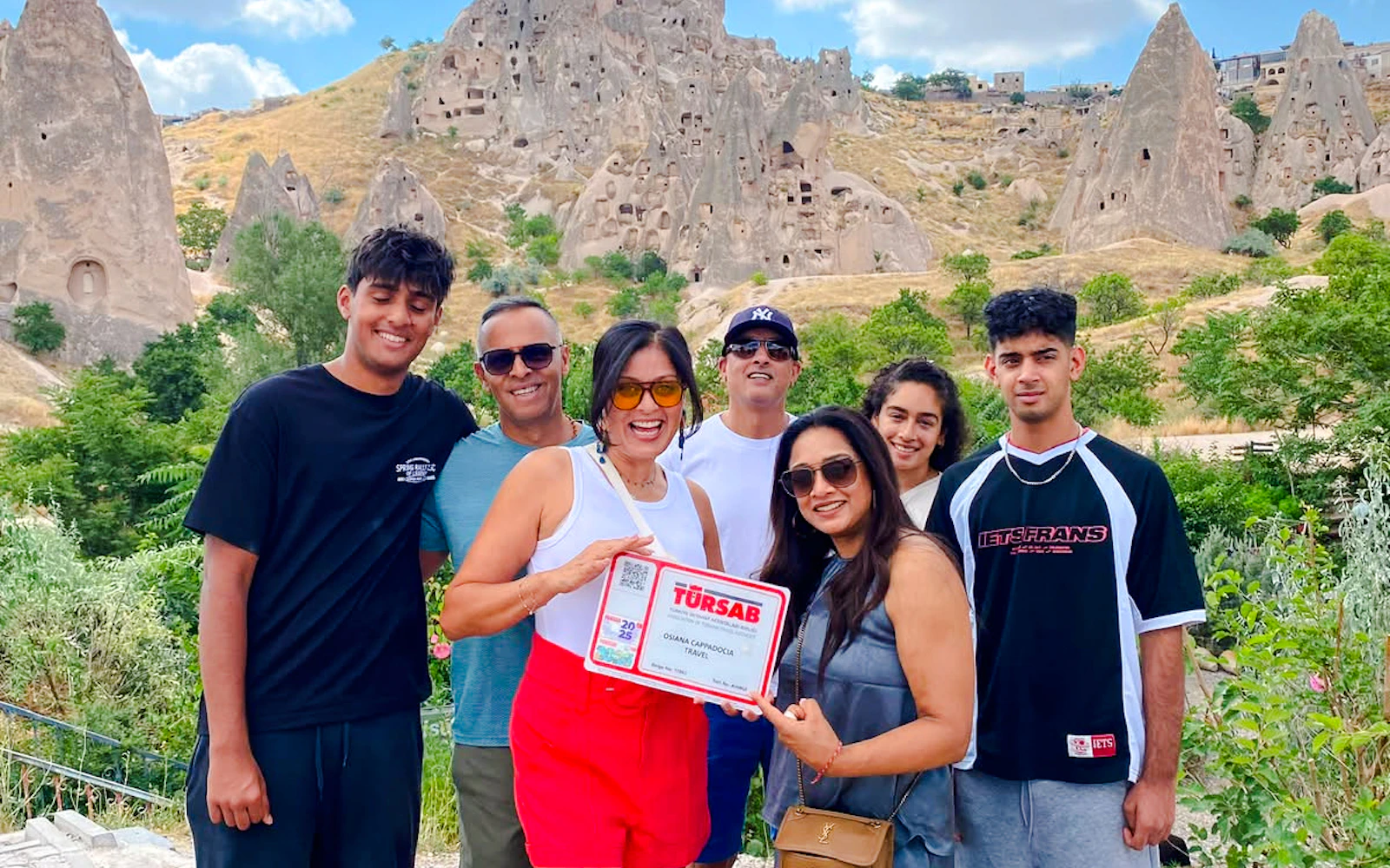Group of tourists at Zelve Open Air Museum, Cappadocia, with rock formations in the background.