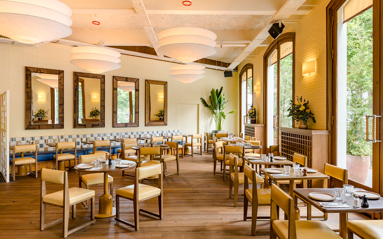 Interior of Brasserie Auteuil with wooden tables, chairs, and large windows.