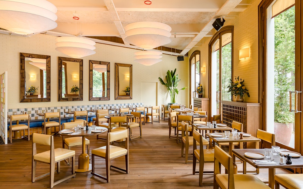 Interior of Brasserie Auteuil with wooden tables, chairs, and large windows.