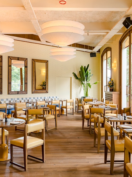Interior of Brasserie Auteuil with wooden tables, chairs, and large windows.