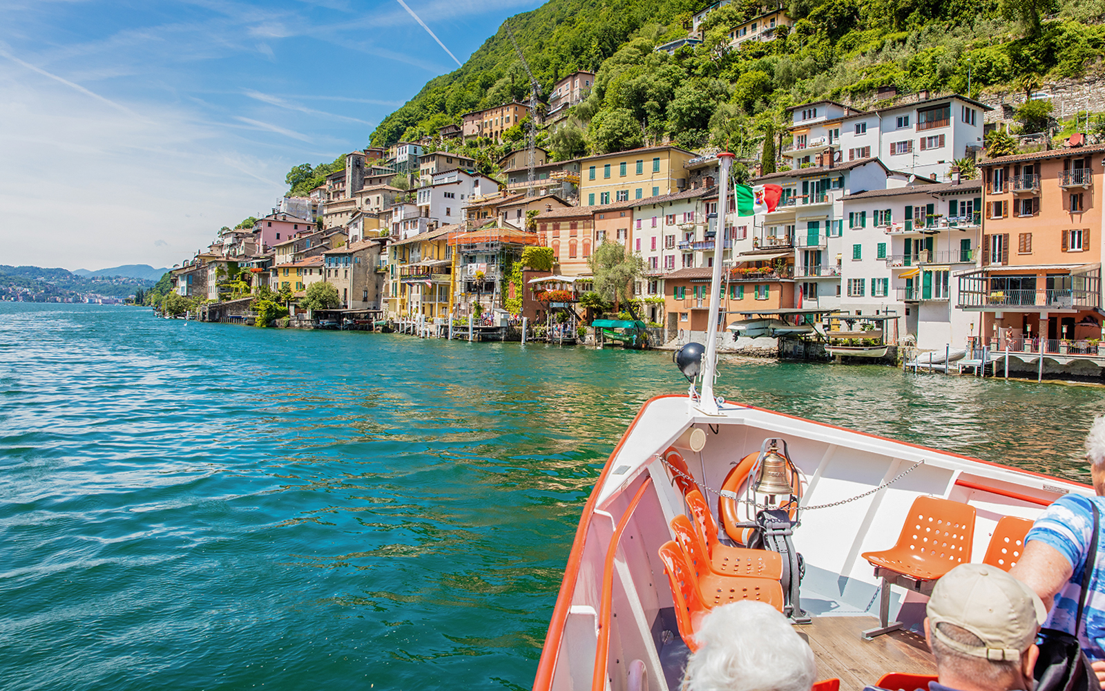 Lake Como boat trip with scenic view of Lugano and surrounding mountains.