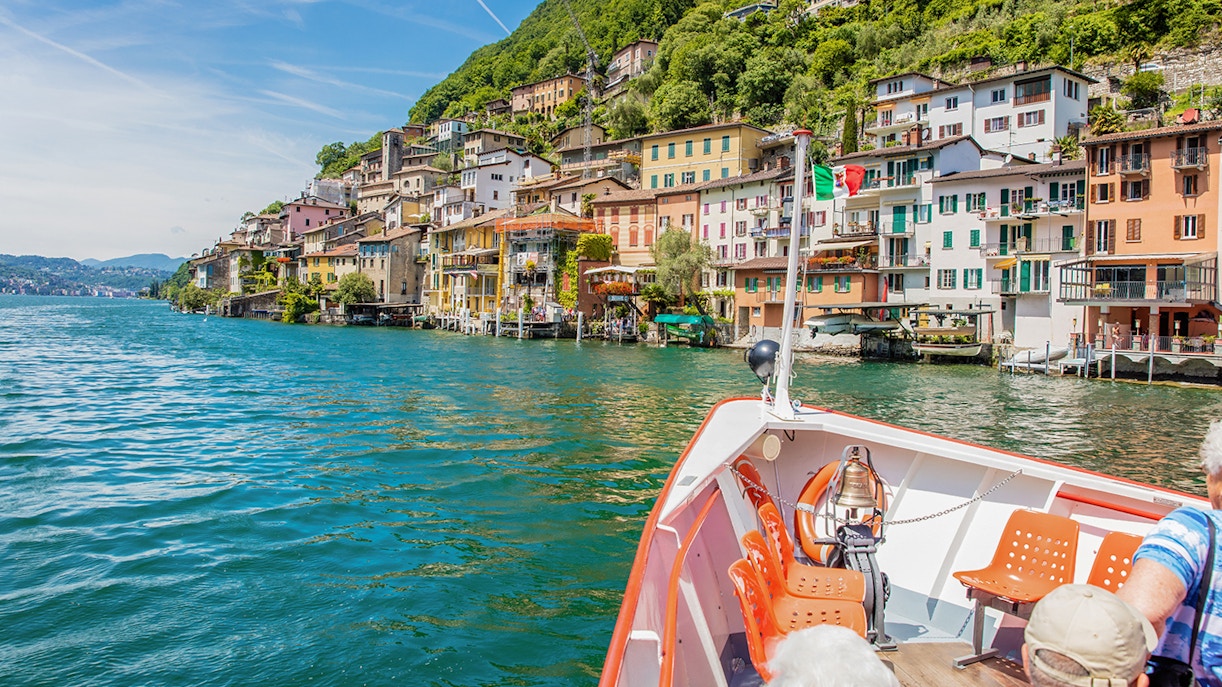 Lake Como boat trip with scenic view of Lugano and surrounding mountains.