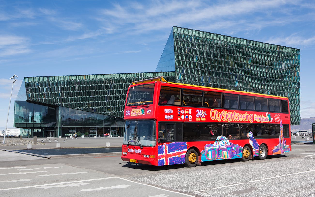 Red double-decker bus in front of Harpa Concert Hall, Reykjavik Hop-on Hop-off City Tour.