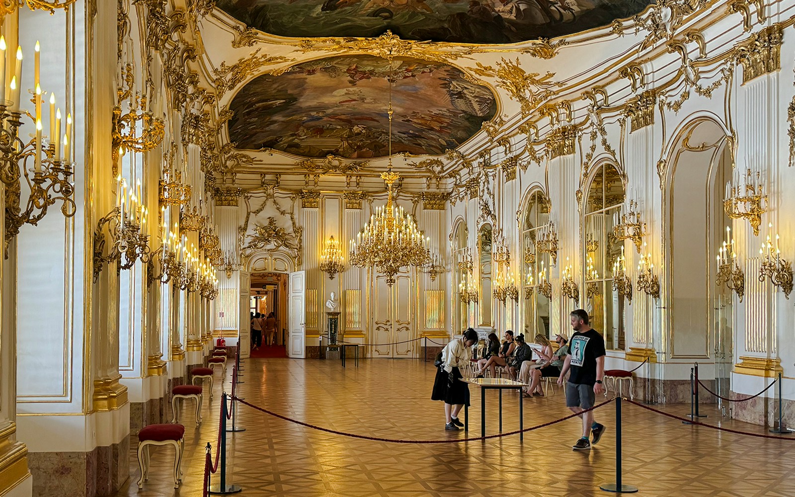 Great Gallery inside Schönbrunn Palace, Vienna with ornate chandeliers and visitors exploring.