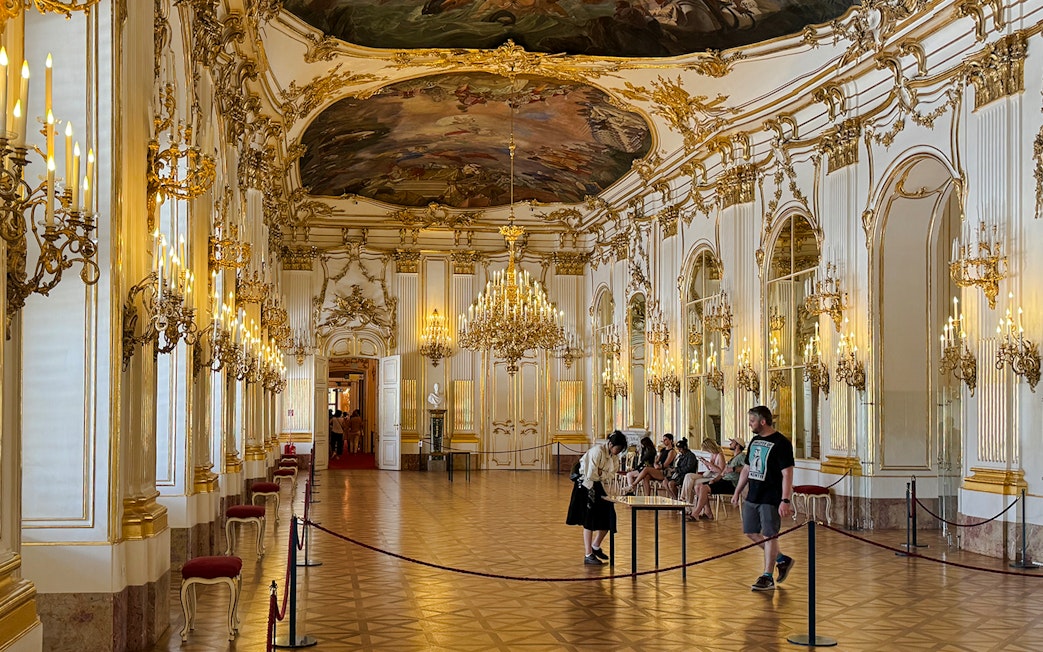 Great Gallery inside Schönbrunn Palace, Vienna with ornate chandeliers and visitors exploring.