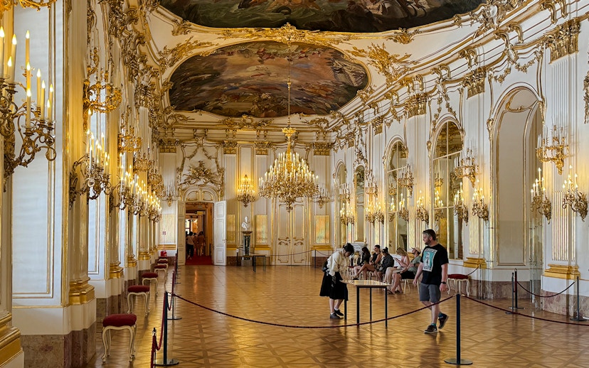 Great Gallery inside Schönbrunn Palace, Vienna with ornate chandeliers and visitors exploring.