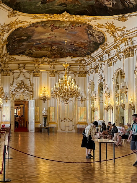Great Gallery inside Schönbrunn Palace, Vienna with ornate chandeliers and visitors exploring.
