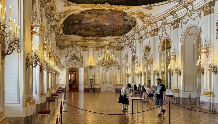 Great Gallery inside Schönbrunn Palace, Vienna with ornate chandeliers and visitors exploring.