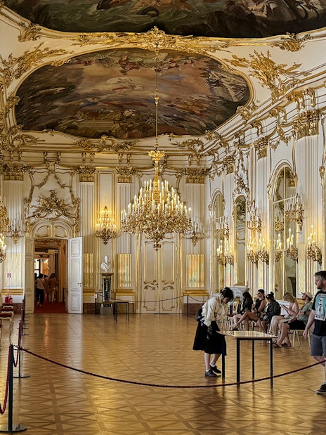 Great Gallery inside Schönbrunn Palace, Vienna with ornate chandeliers and visitors exploring.