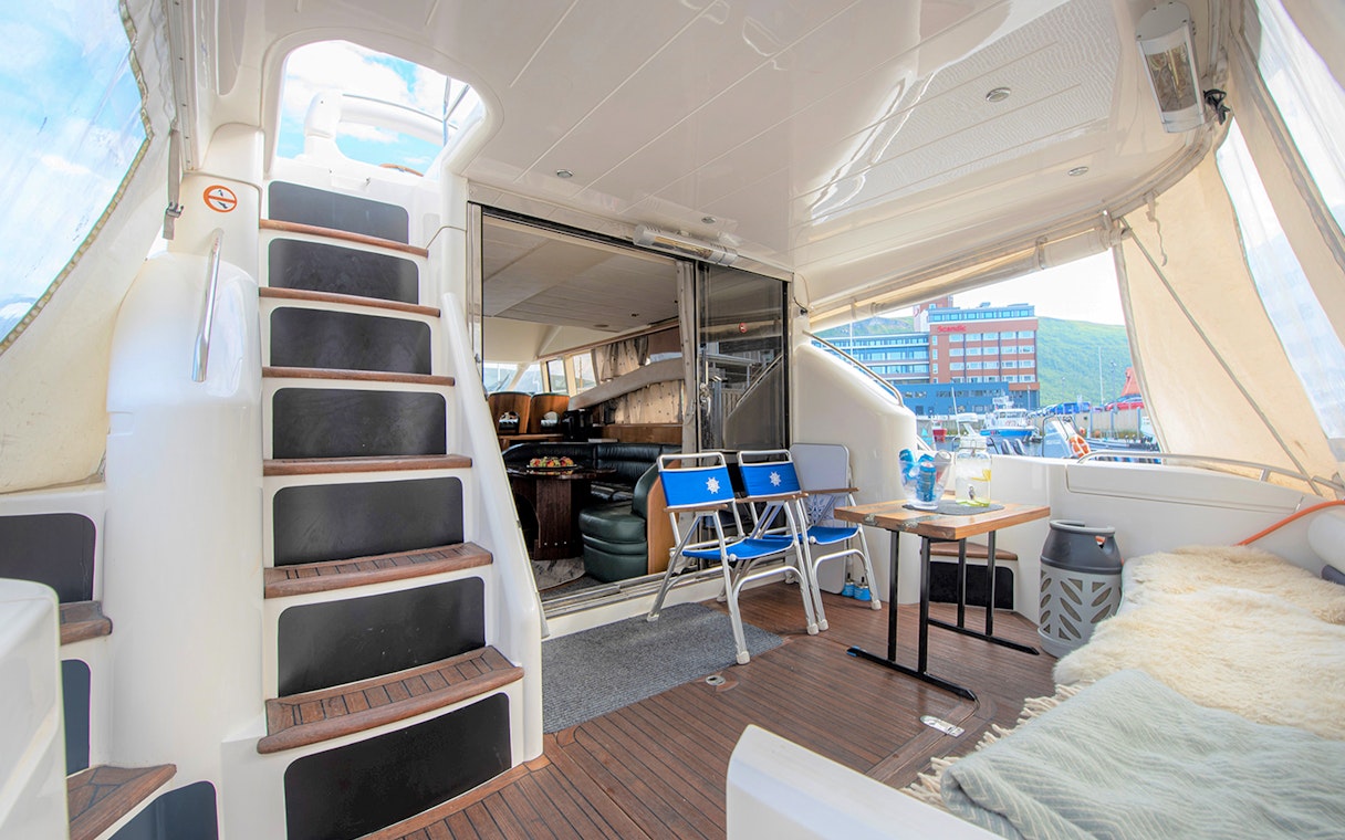 Inside view of a Whale Watching boat in Skjervøy with seating and table setup.