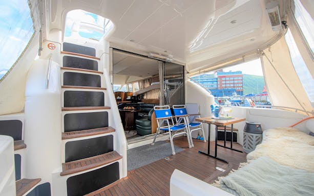 Inside view of a Whale Watching boat in Skjervøy with seating and table setup.