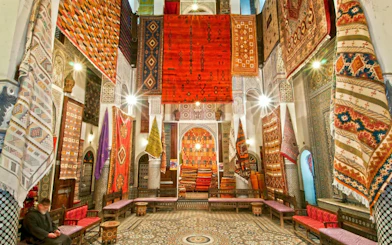 Colorful Moroccan rugs displayed in a Fes souk during a city tour.