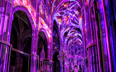 Vibrant light display inside Votivkirche, Vienna, showcasing colorful illuminated arches.