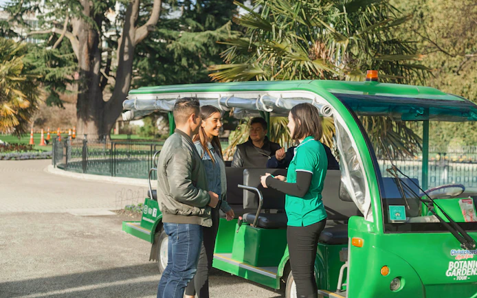 Tour guide with visitors at Christchurch Botanic Gardens tour vehicle.