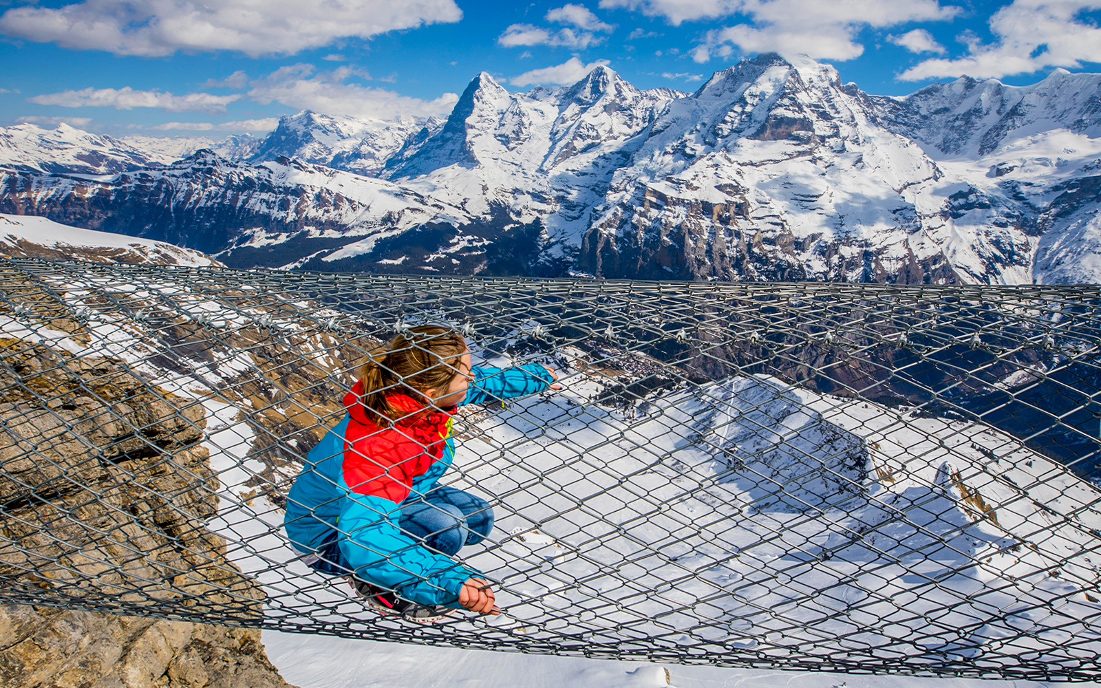 Person on a netted platform with snowy Swiss Alps view during Interlaken trip from Geneva.