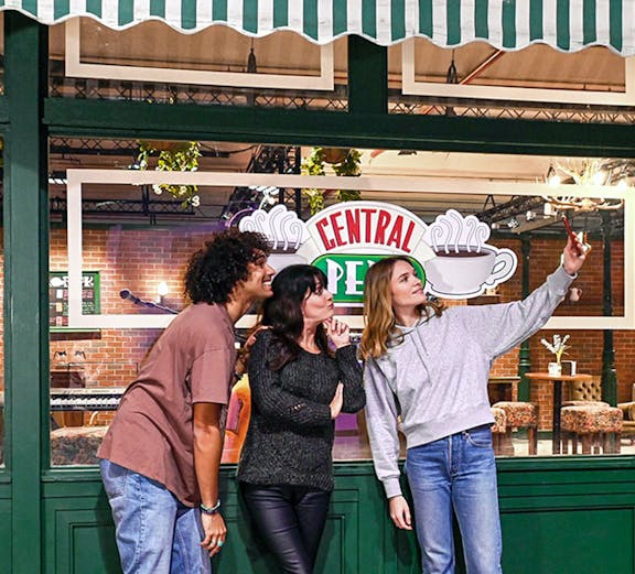 Visitors taking a selfie at Central Perk set during The Friends Experience tour.