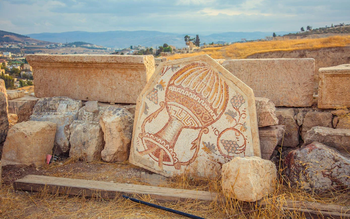 Old Roman mosaic with wine jar and grape in Jerash, Jordan.