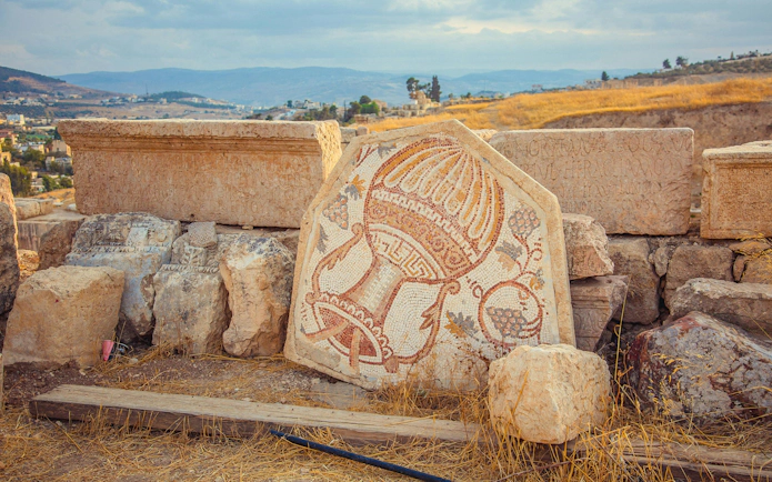 Old Roman mosaic with wine jar and grape in Jerash, Jordan.