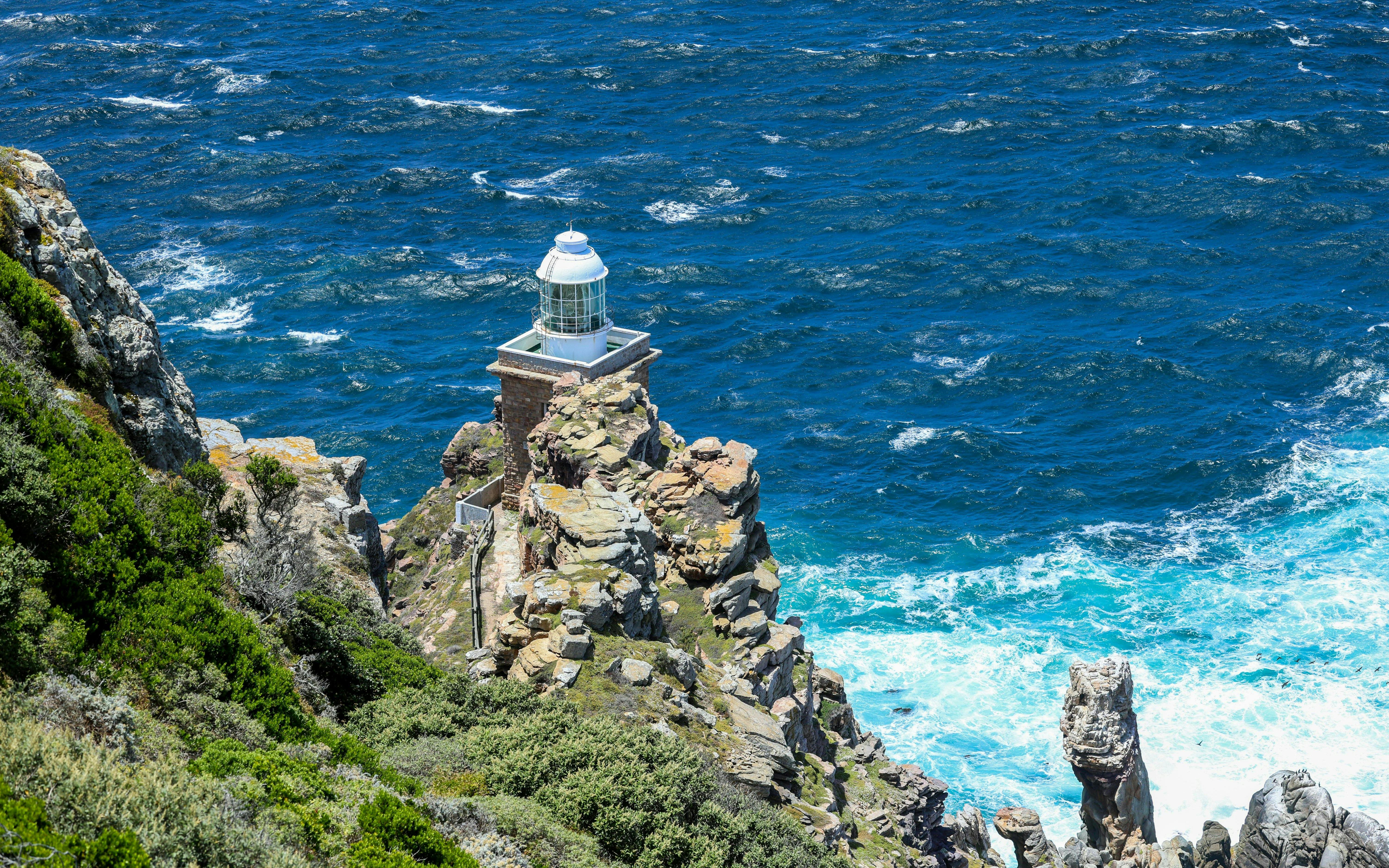 Cape Point lighthouse on rocky cliff overlooking the ocean in South Africa.