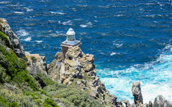 Cape Point lighthouse on rocky cliff overlooking the ocean in South Africa.